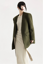 Person wearing a green coat over a white outfit on a white background