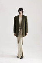 Person wearing a green coat and beige pants on a white background