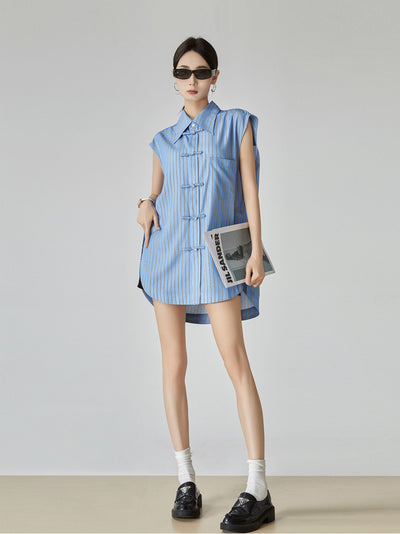 Woman wearing a blue striped dress holding a newspaper against a plain background