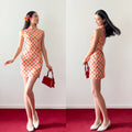 Woman in a red and white checkered dress holding a red handbag on a red carpet with a white background