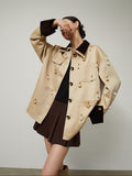 Woman wearing a beige trench coat with gold buttons on a plain background