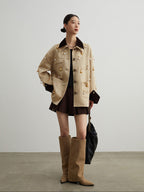 Woman wearing a beige jacket, black dress, and tan knee-high boots against a plain background