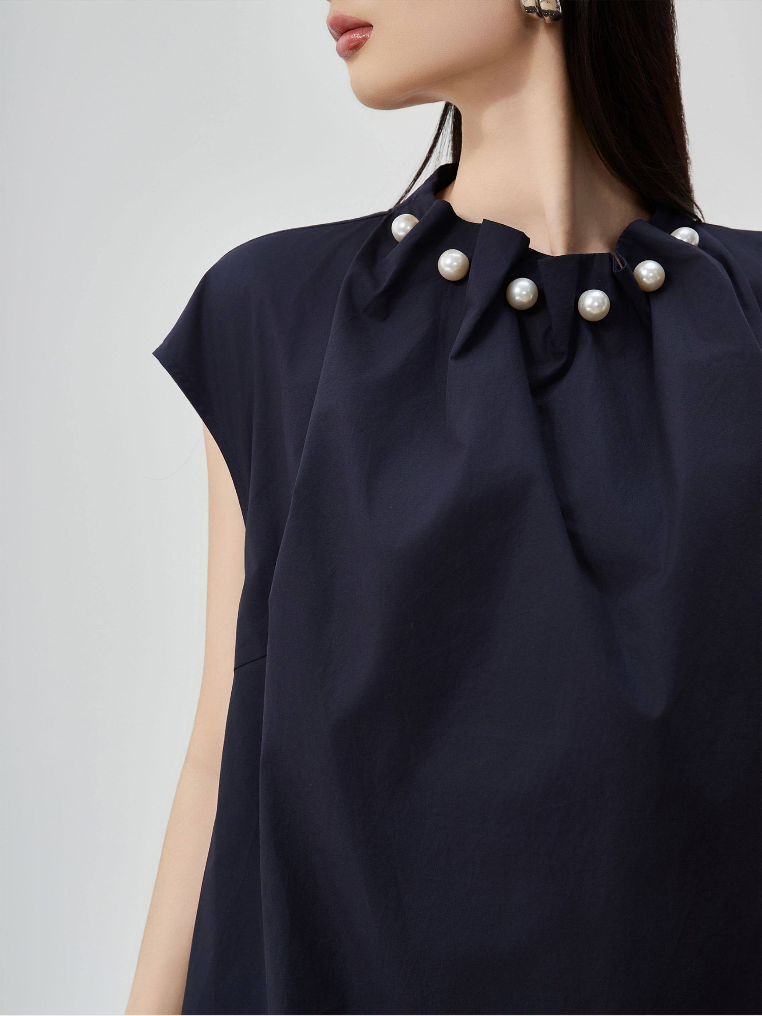Navy blue dress with pearl embellishments on a plain background