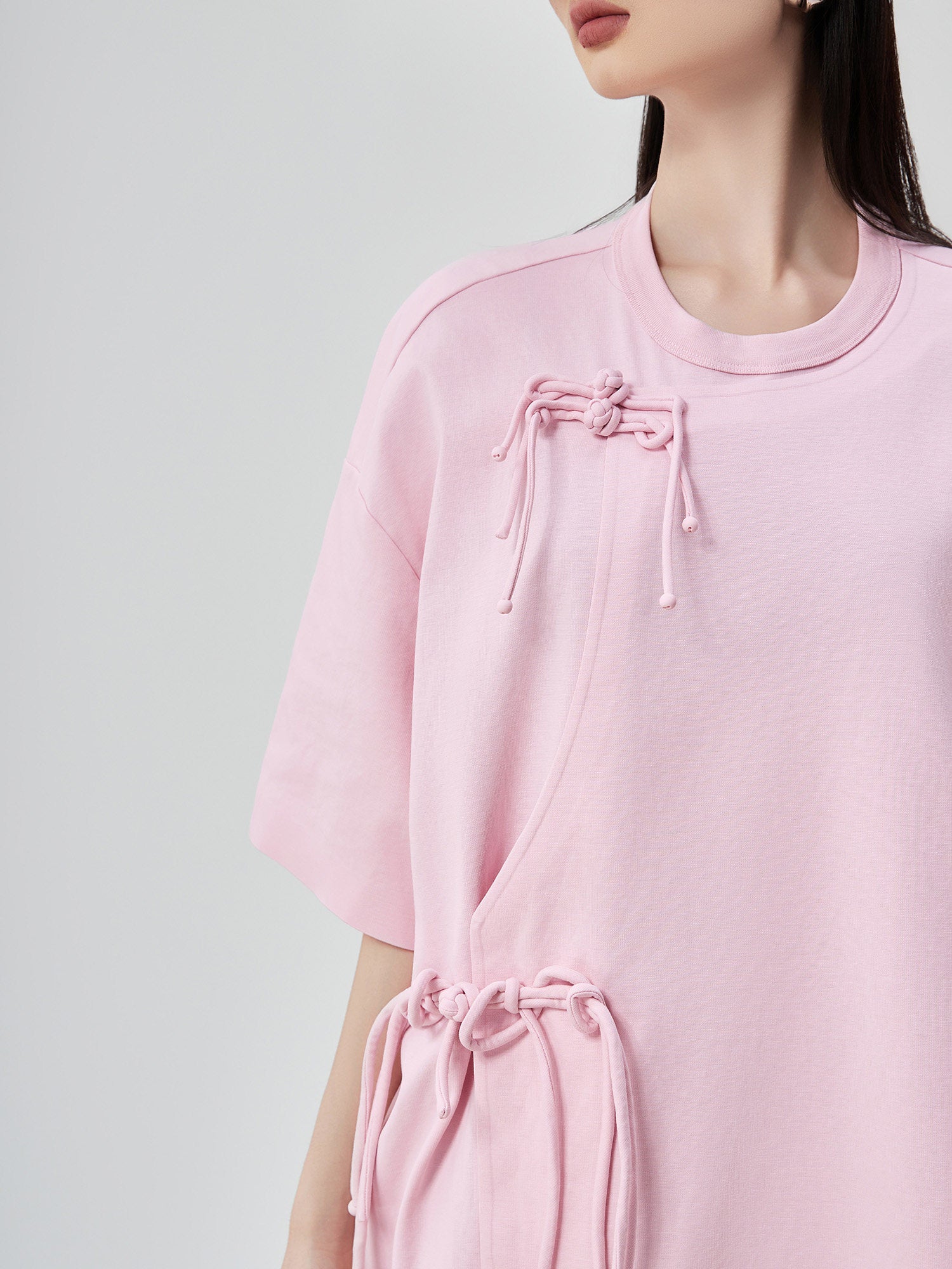 Pink dress with drawstring details on a plain background