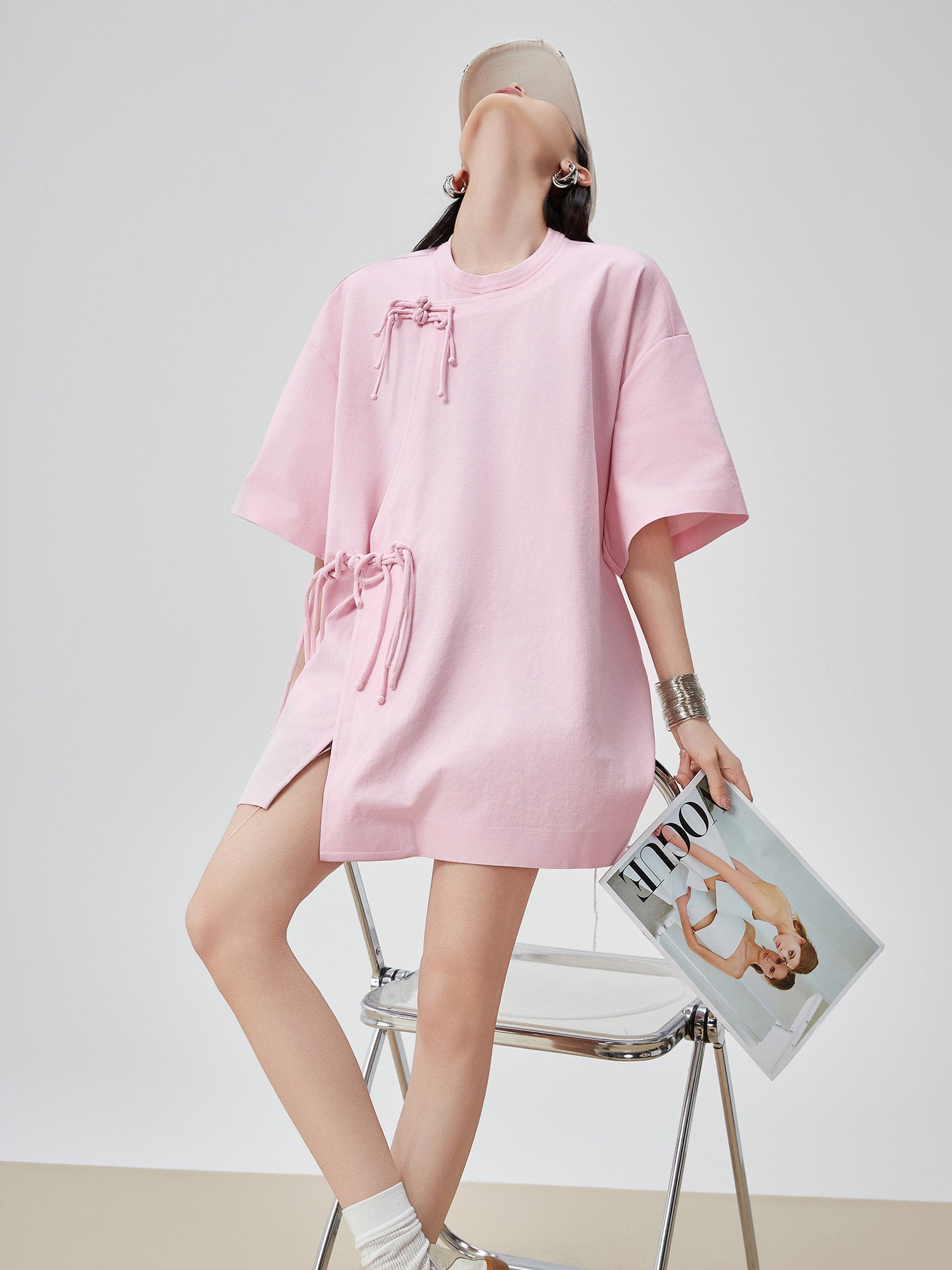 Person wearing a pink dress holding a magazine on a white background