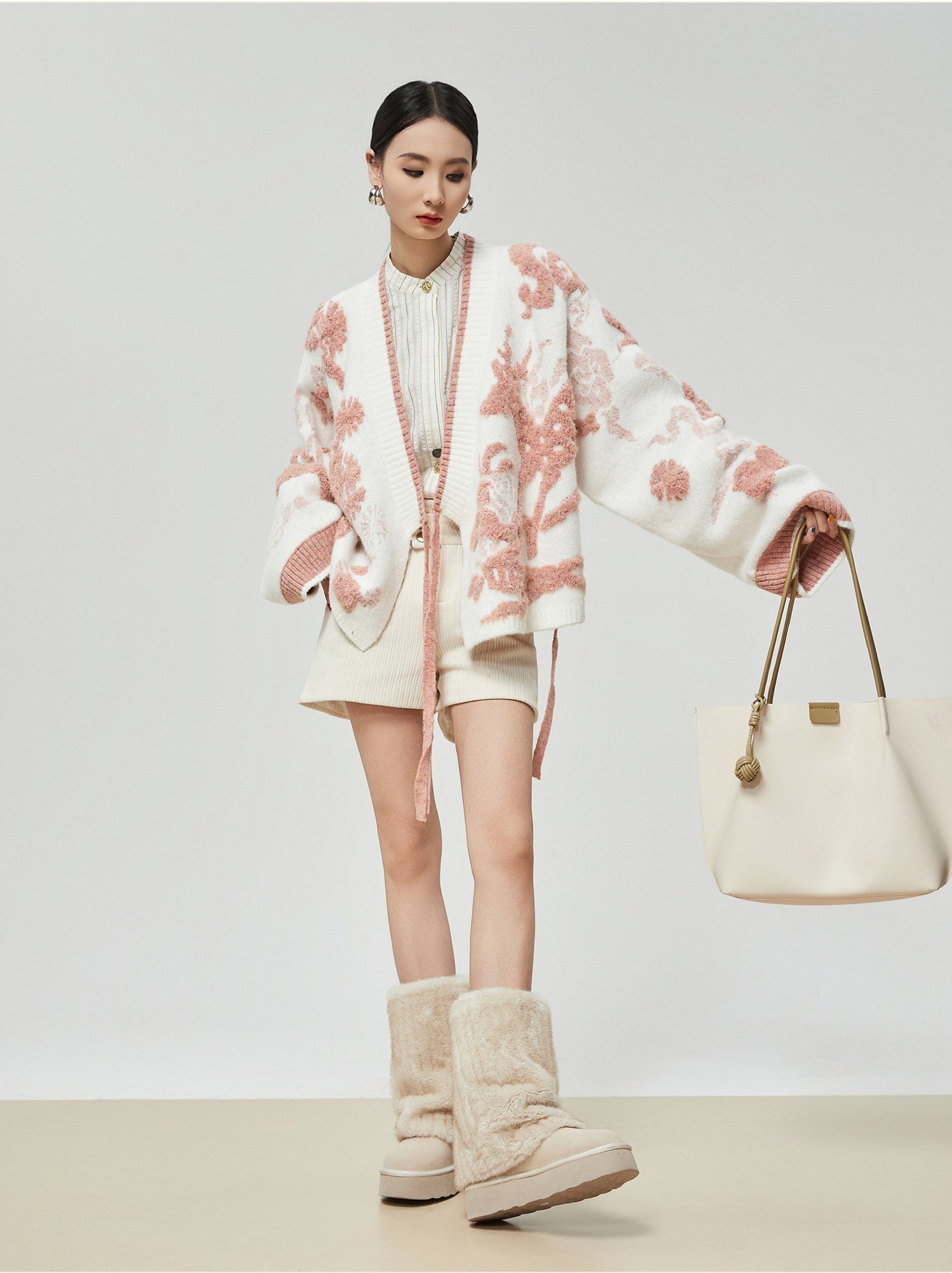 Woman wearing a floral coat and holding a handbag on a plain background