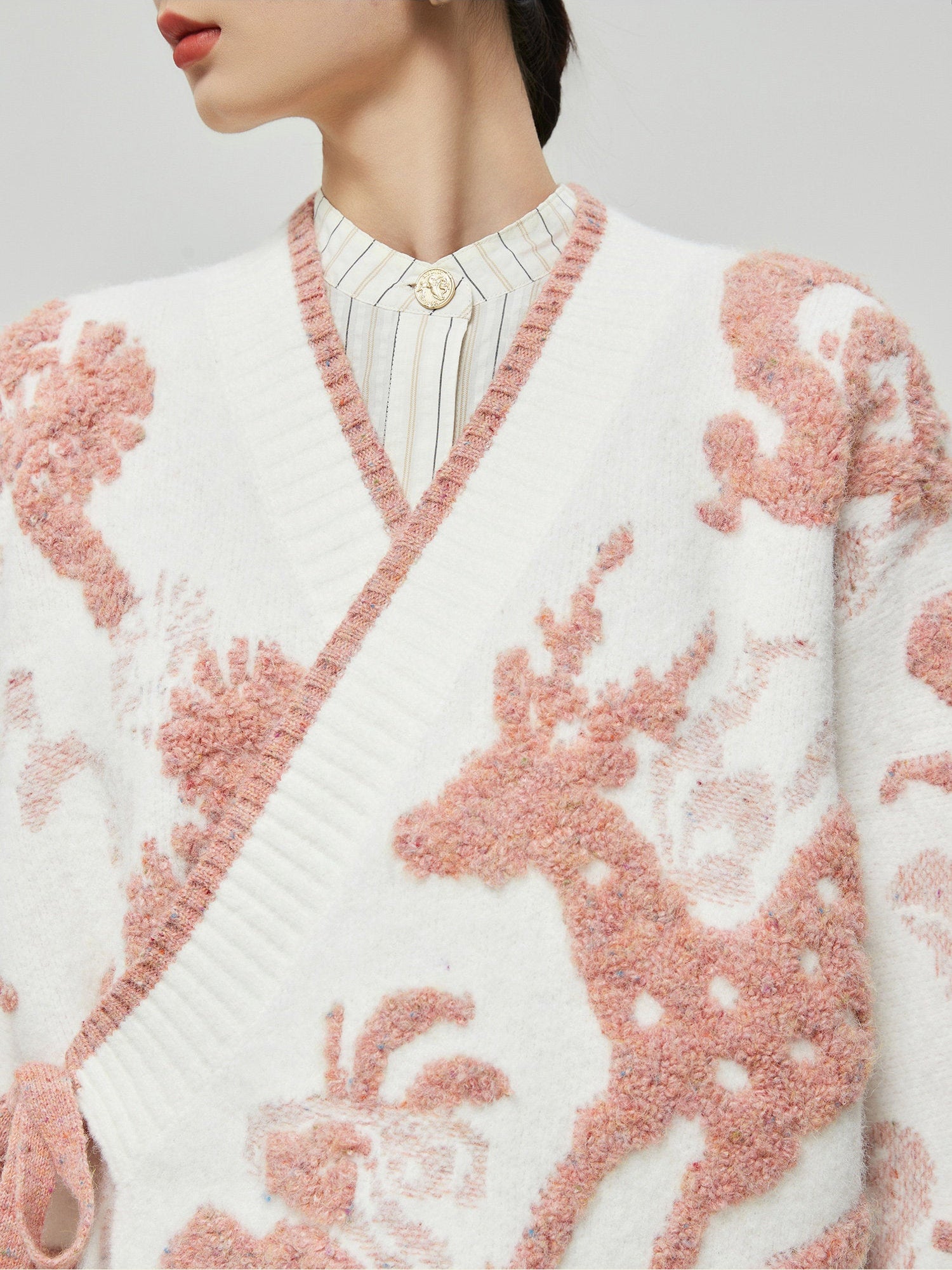 White cardigan with pink deer pattern worn by a woman