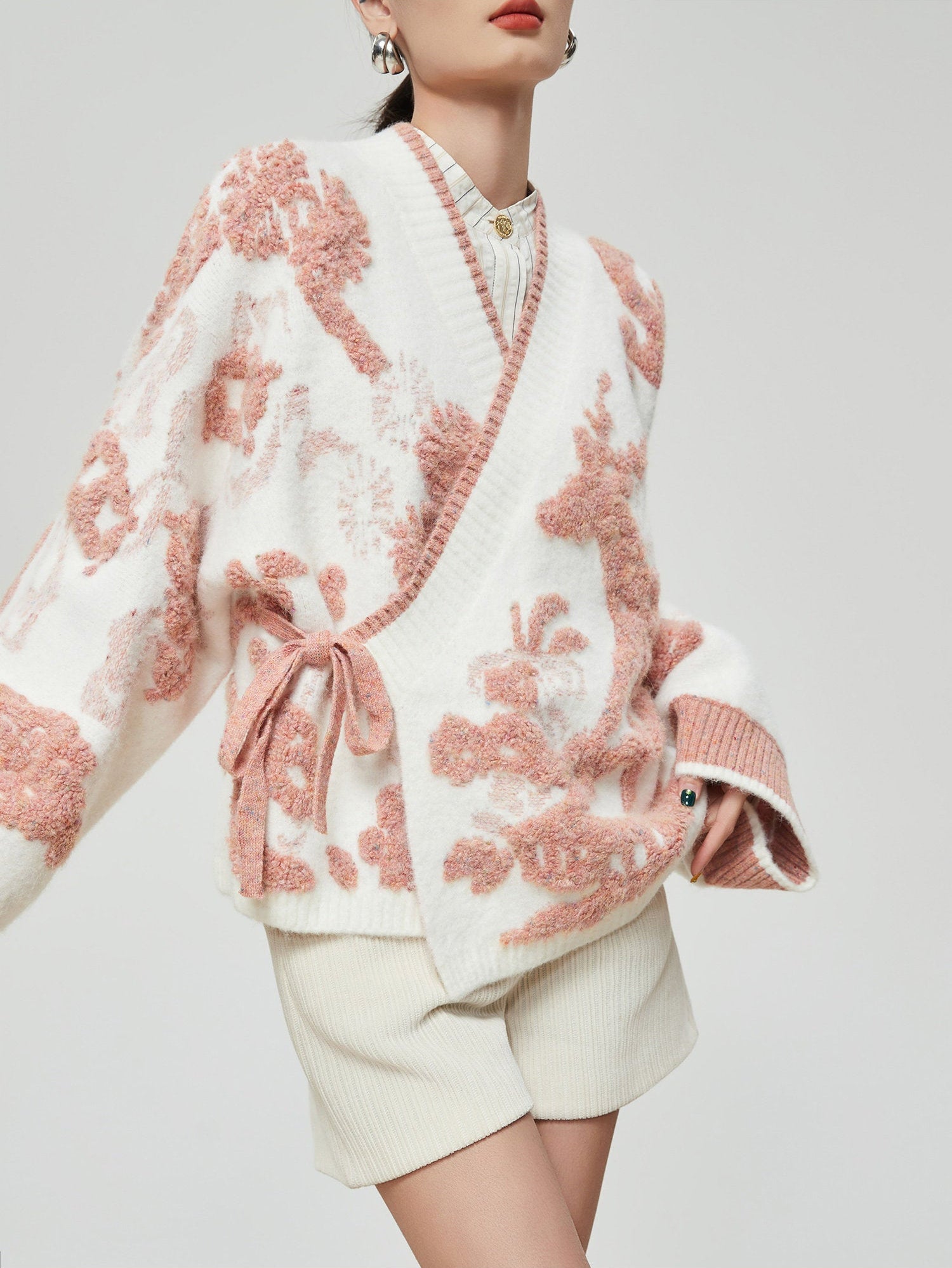 Woman wearing a white and pink floral patterned outfit on a plain background