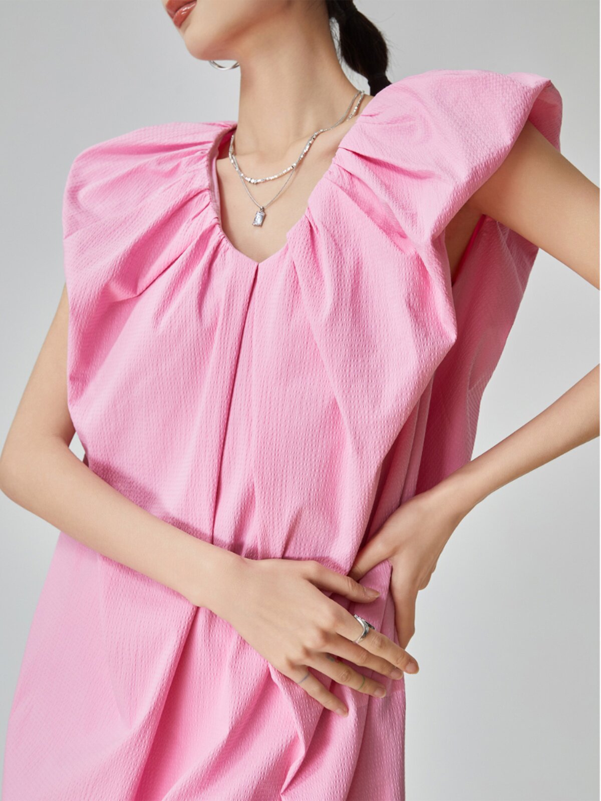 Person wearing a pink dress with a plain background