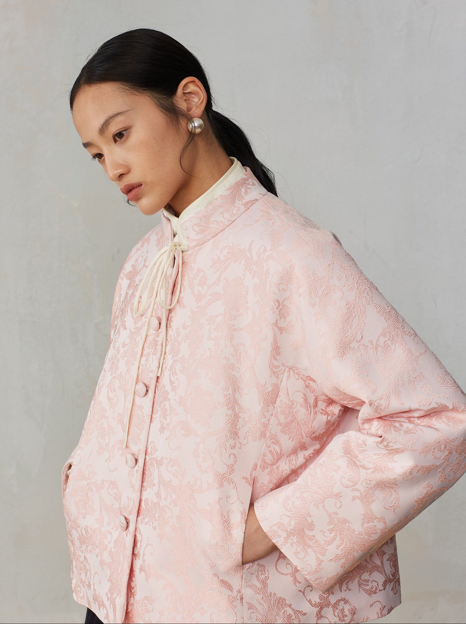 Woman wearing a pink floral blouse against a plain background