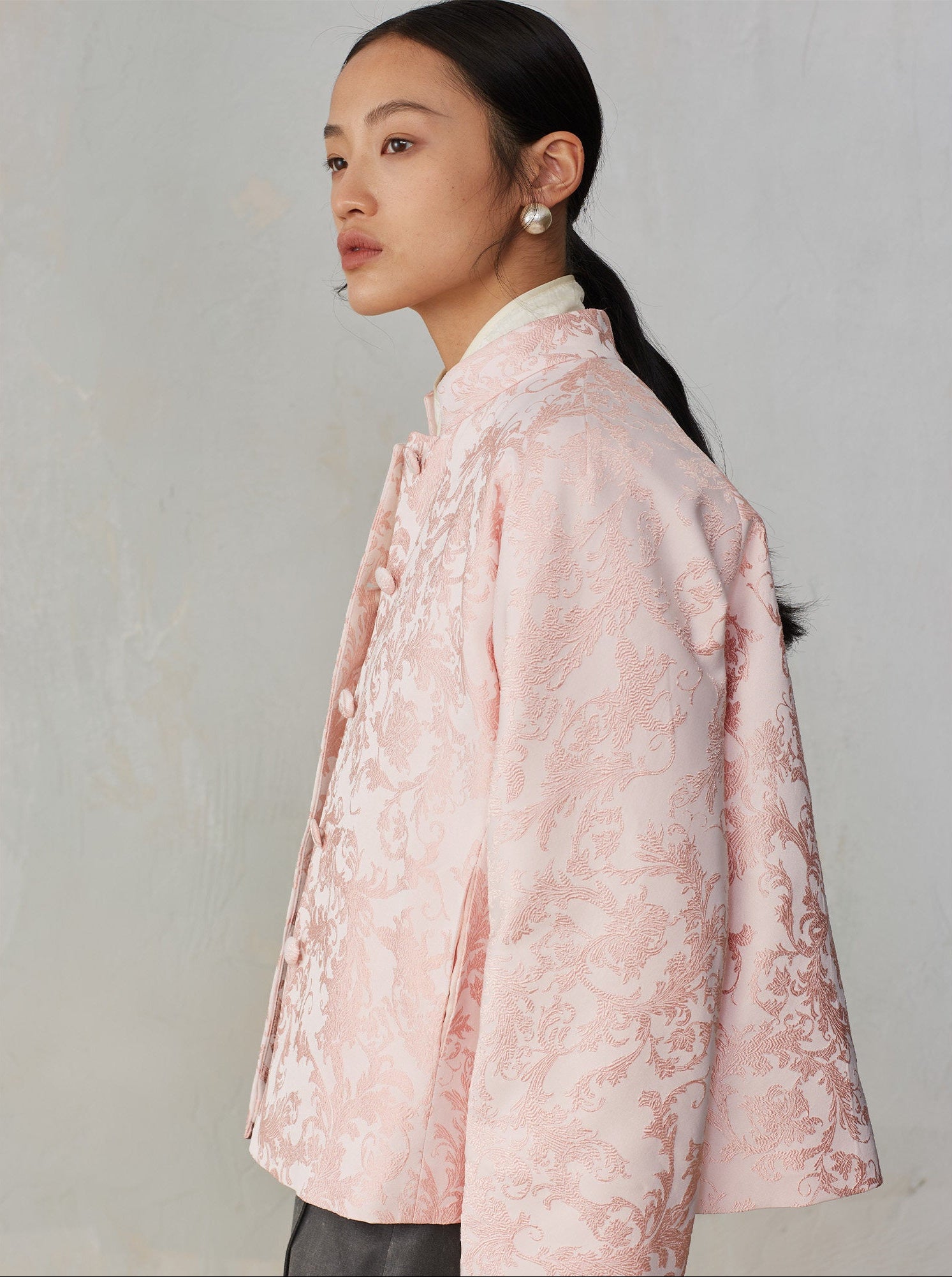 Woman wearing a pink floral coat against a plain background