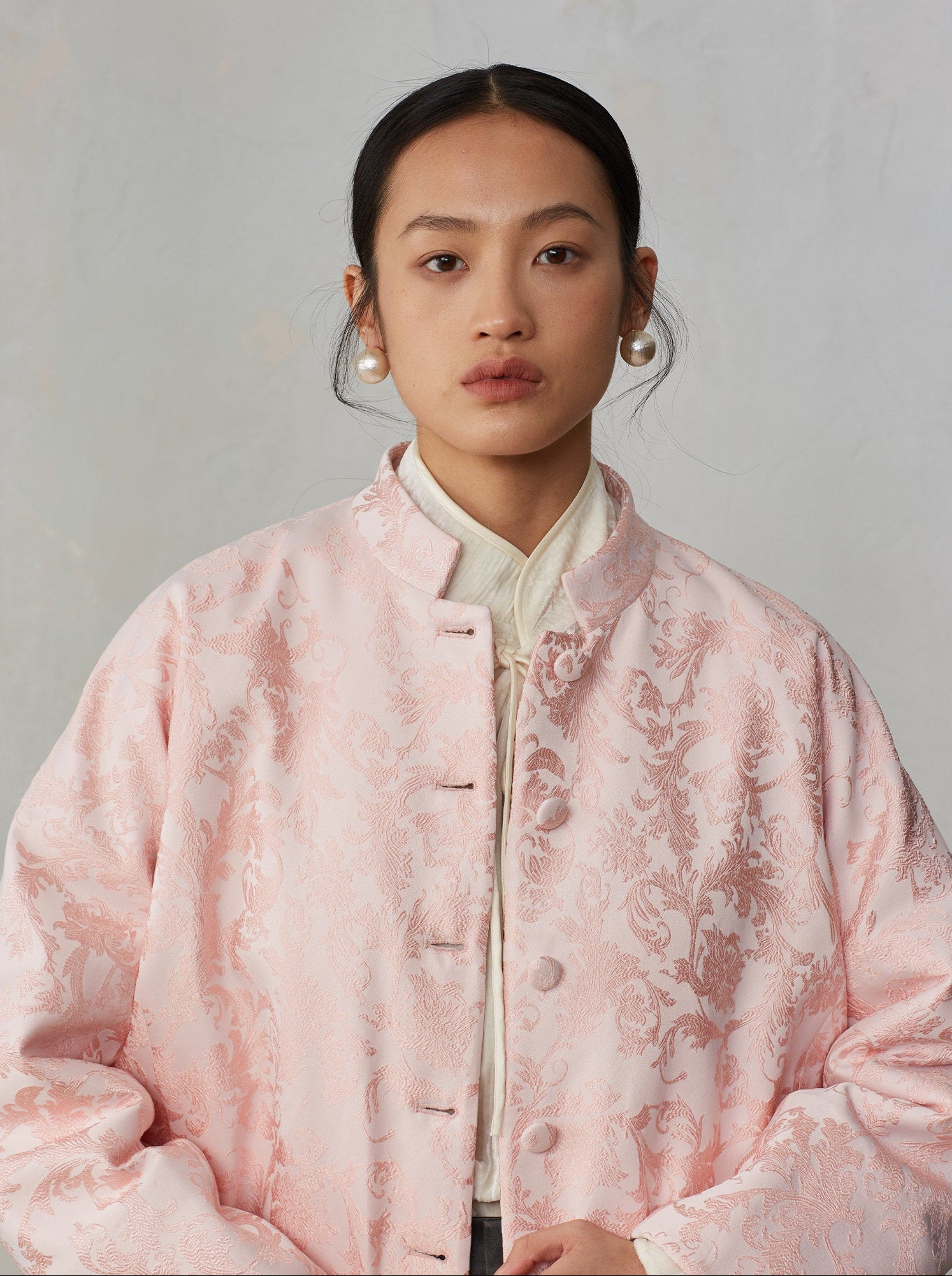 Person wearing a pink floral patterned coat against a plain background