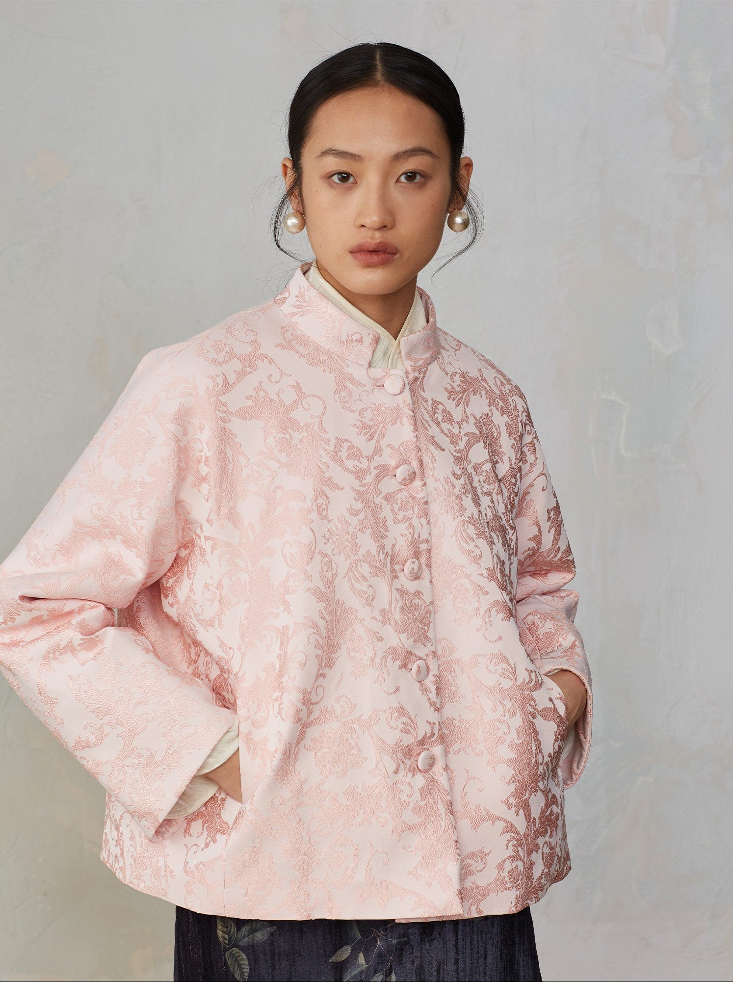 Person wearing a pink floral patterned jacket against a plain background