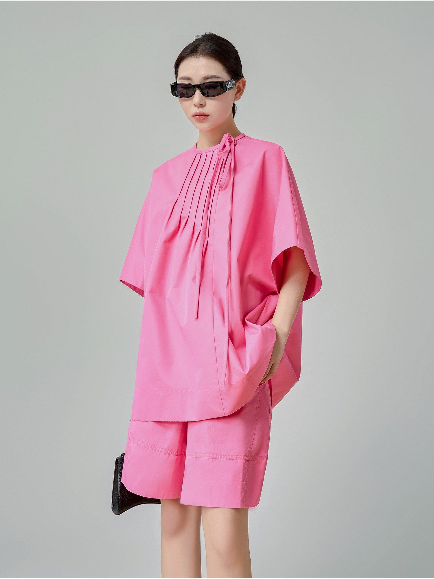 Person wearing a pink outfit with a plain background