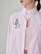 Pink striped shirt with a decorative butterfly design on a gray background