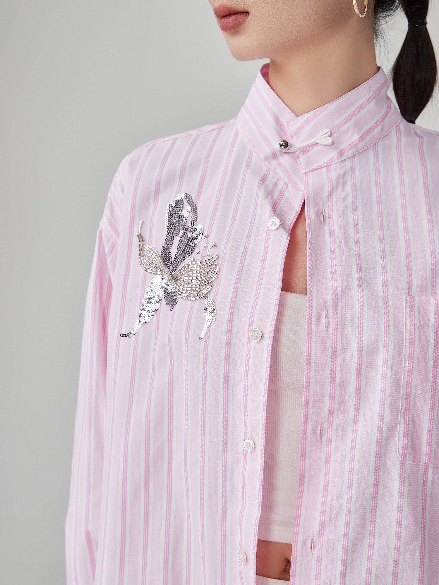 Pink striped shirt with a decorative butterfly design on a gray background