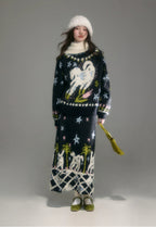 Person wearing a long, dark blue sweater with unicorn designs on a plain background
