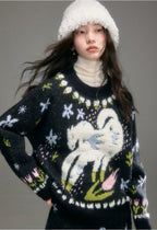 Person wearing a black sweater with a white cat design and a white hat on a gray background