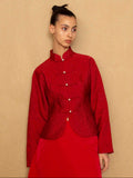 Woman wearing a red jacket and skirt against a beige background
