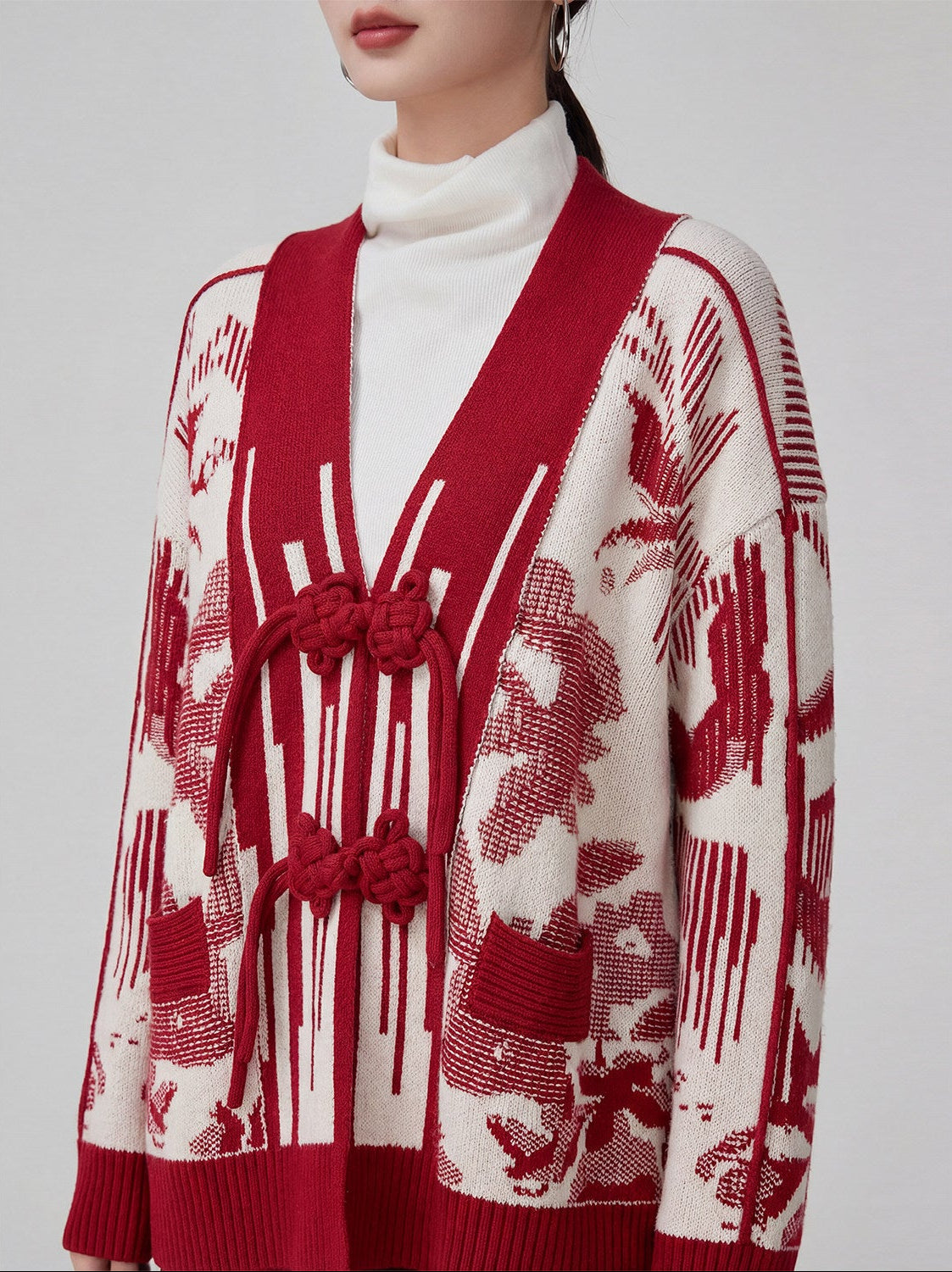 Red and white patterned cardigan worn by a person on a light gray background