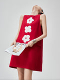 Woman wearing a red dress with white floral patterns, holding a magazine.