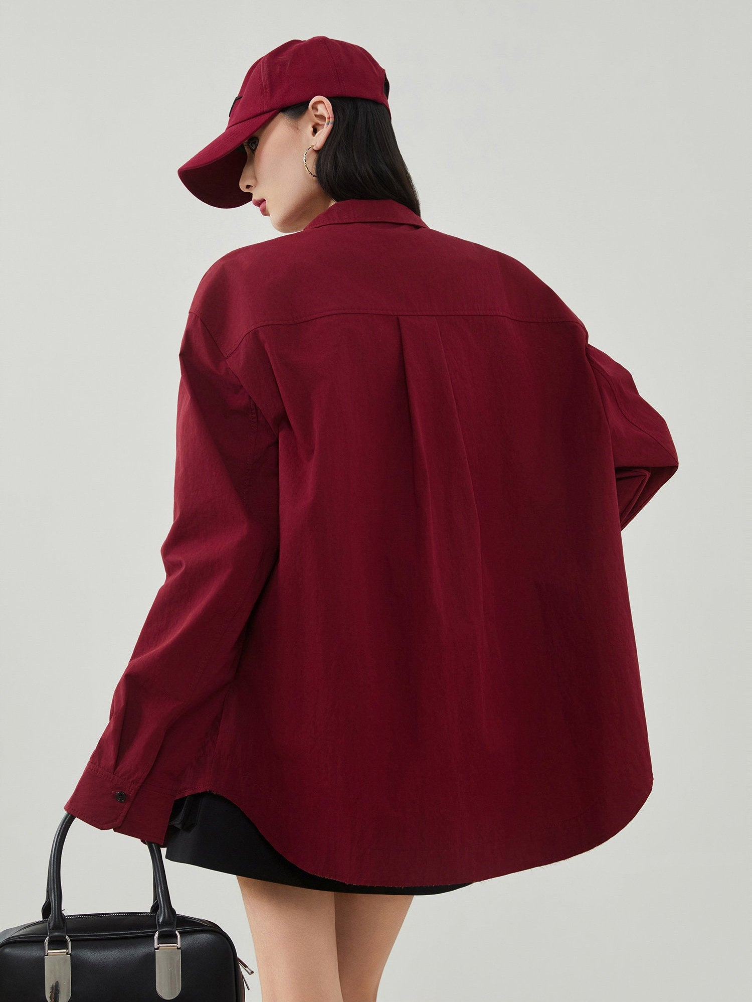 Person wearing a burgundy jacket and cap on a plain background