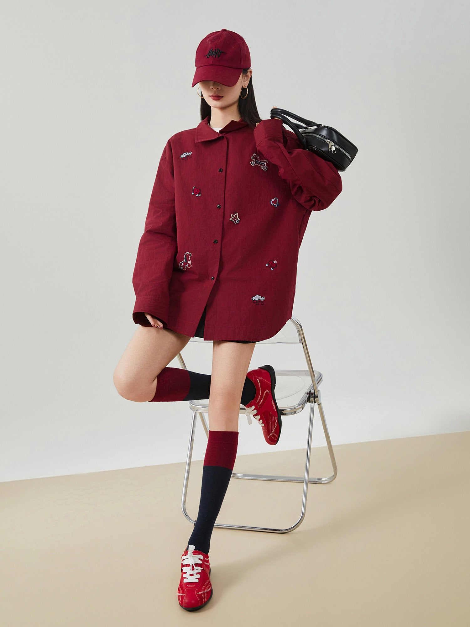 Person wearing a red coat, hat, and shoes with a black bag on a white background