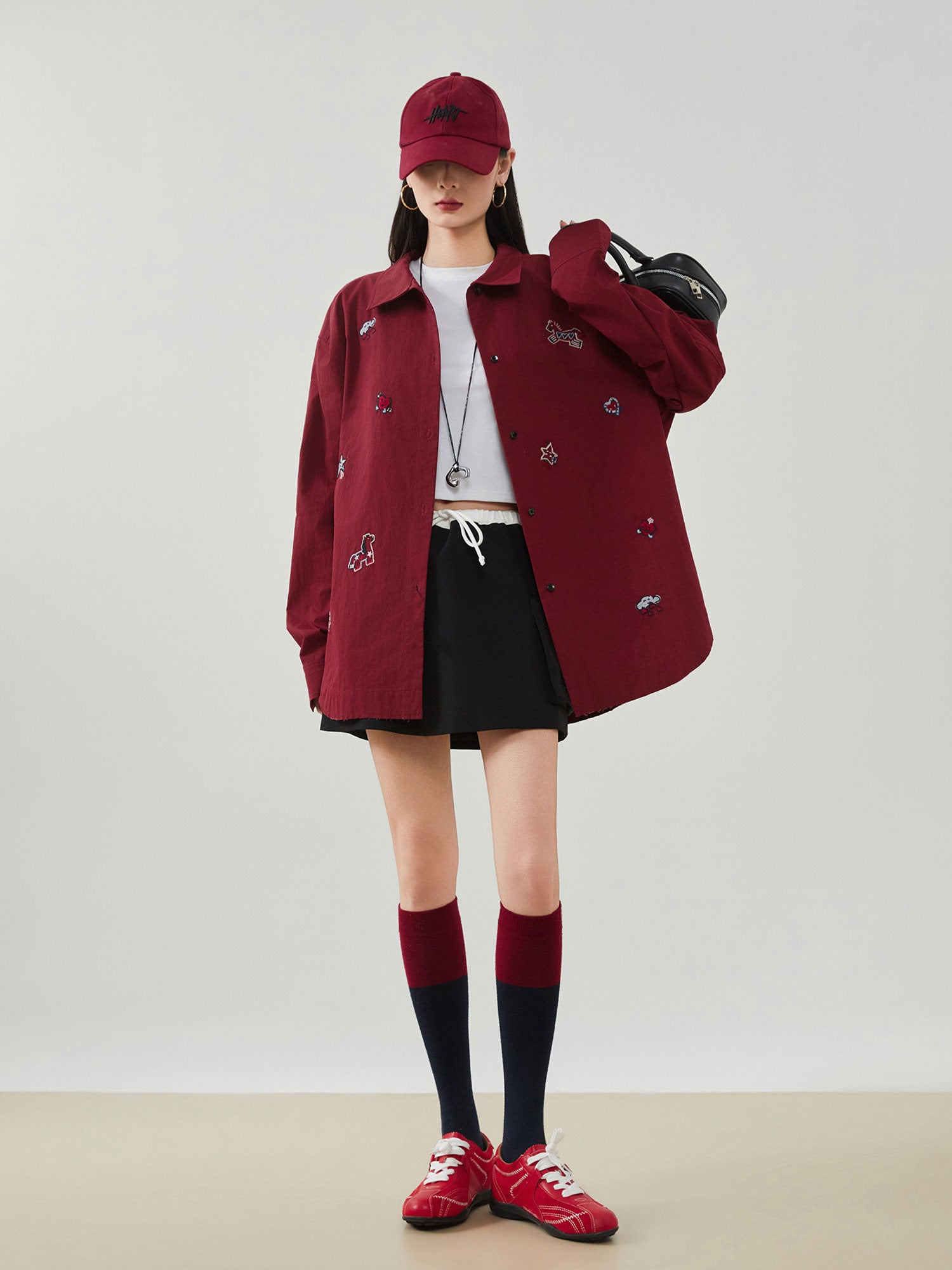 Person wearing a red coat, cap, and shoes with a plain background