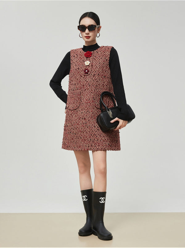 Woman wearing a patterned dress with a black top and rain boots on a plain background