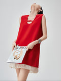 Woman wearing a red sleeveless dress holding a magazine on a gray background