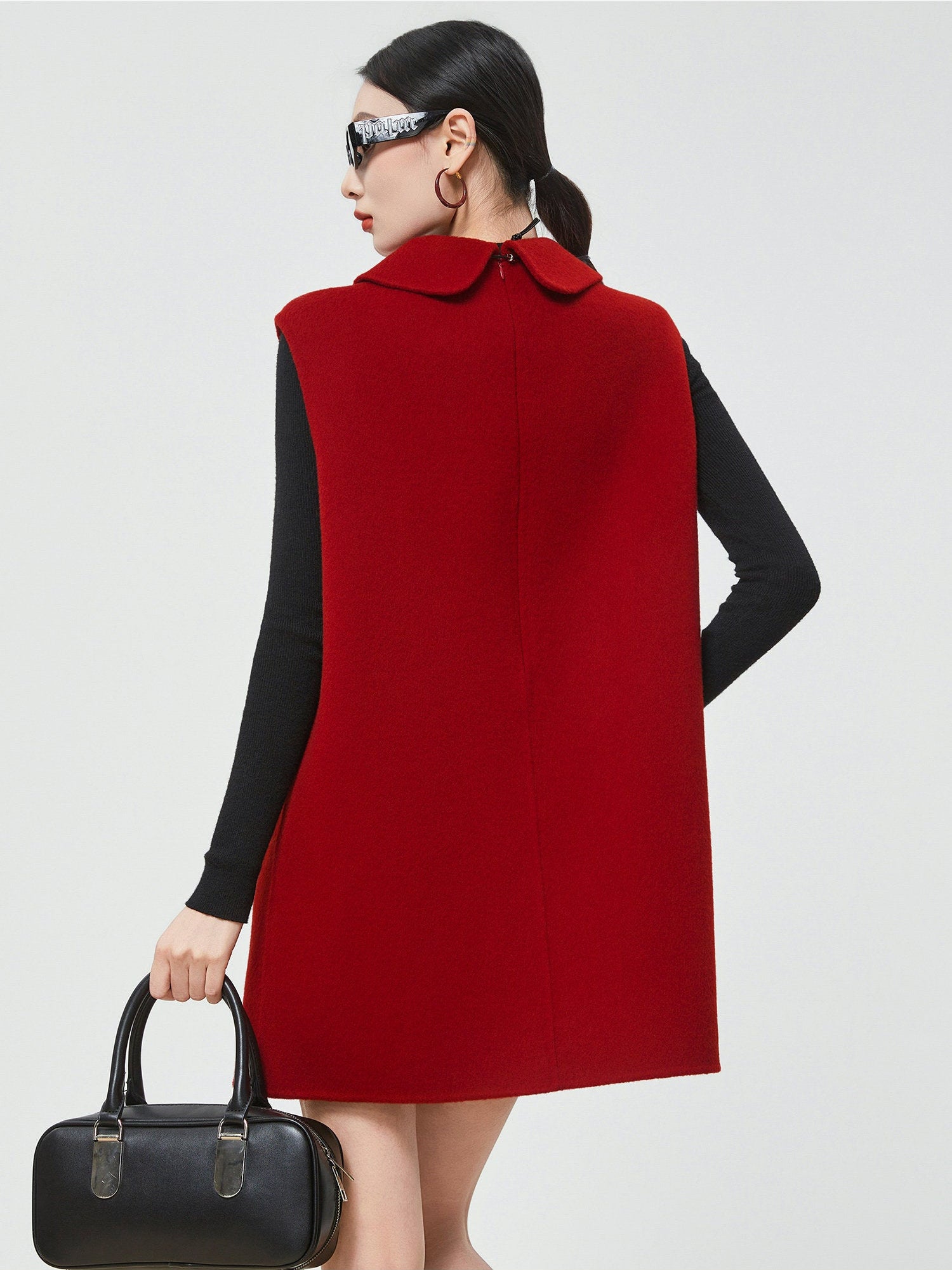 Woman wearing a red vest over a black long-sleeve shirt on a white background