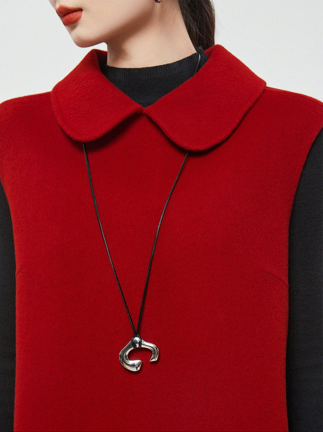 Red garment with a black necklace featuring a silver clasp on a white background