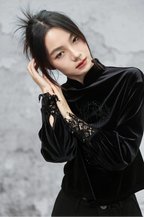 Woman wearing a black outfit with lace details against a gray background