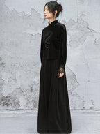 Woman wearing a black dress with lace sleeves against a textured gray wall.