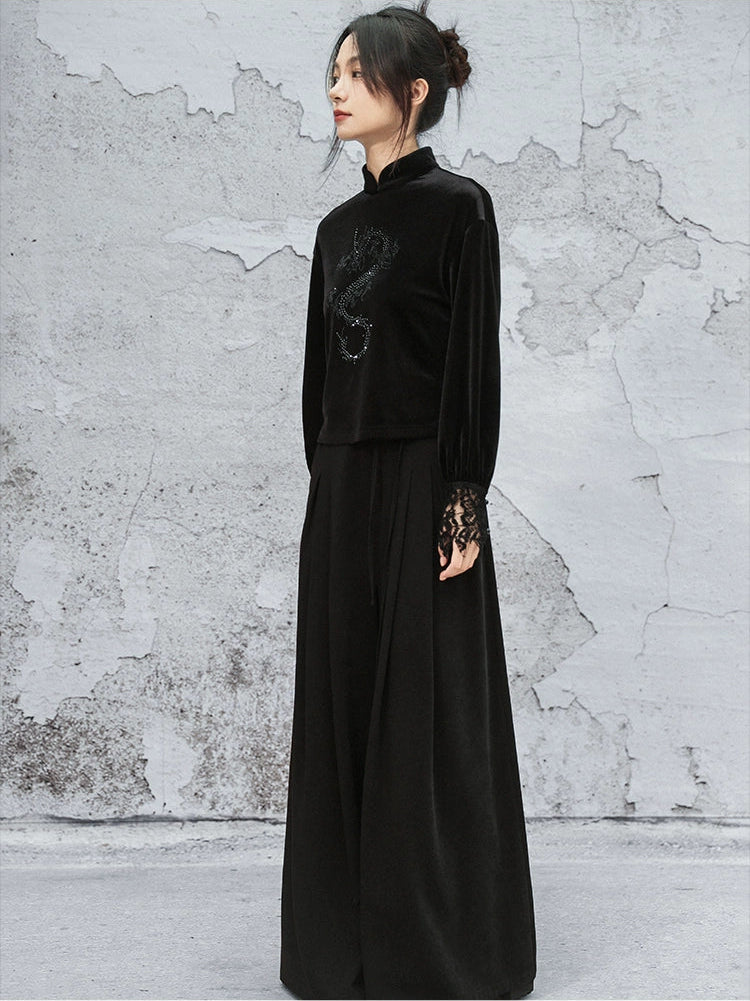 Woman wearing a black dress with lace sleeves against a textured gray wall.