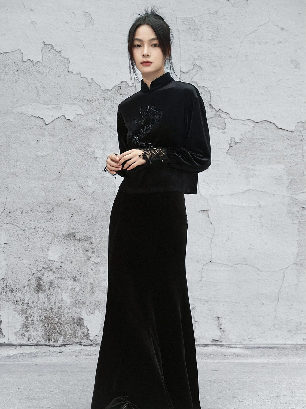 Woman wearing a black outfit against a textured gray wall