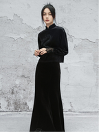 Woman wearing a black outfit against a textured gray wall