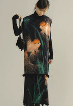 Woman wearing a black dress with goldfish and seaweed pattern on a plain background