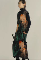 Woman wearing a long, dark-colored dress with abstract patterns on a plain background