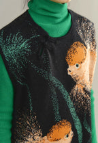 Sweater with a graphic design of a person and plants, worn over a green turtleneck.