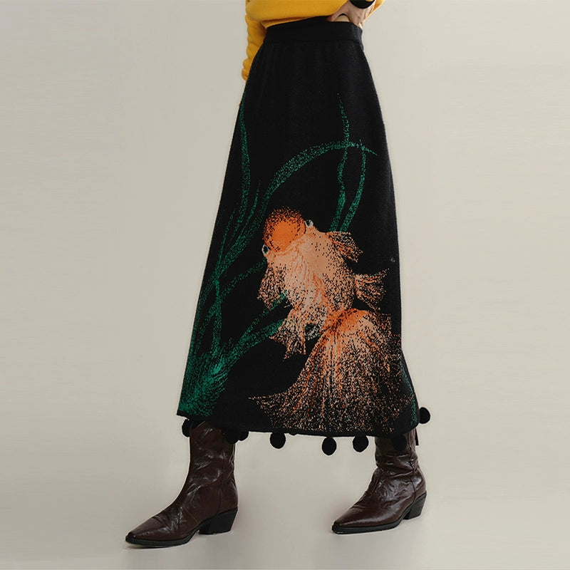 Person wearing a black skirt with goldfish design on a plain background