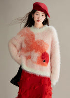 Person wearing a fluffy pink sweater with orange floral patterns and a red cap on a neutral background