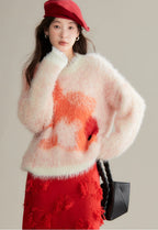 Woman wearing a fluffy pink and orange sweater with a red skirt and hat, holding a black handbag.