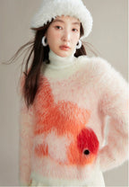 Woman wearing a fluffy white sweater with a red floral design on a plain background