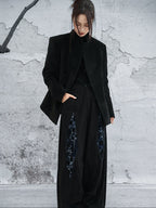 woman standing wearing a velvet suit jacket against a grey background.  