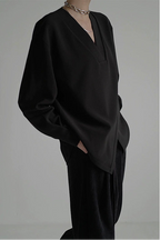 Person wearing a black outfit against a gray background