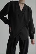 Person wearing a black outfit with a draped design on a gray background