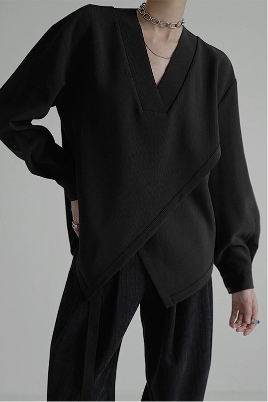 Person wearing a black outfit with a draped design on a gray background