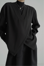 Black outfit with a V-neck top and long sleeves on a gray background