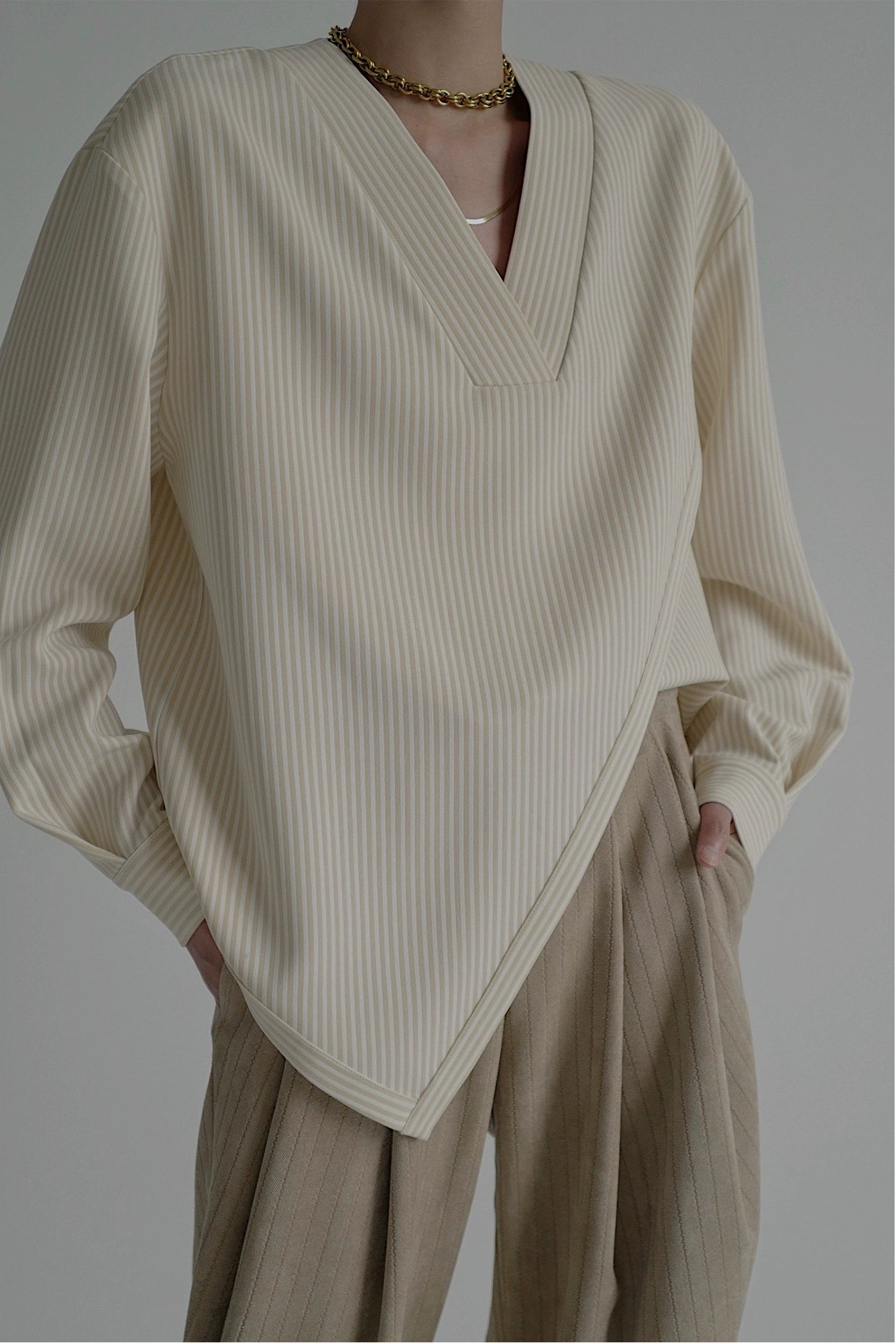 Person wearing a beige ribbed sweater and beige pants against a plain background